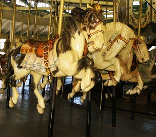 A group of horses on a merry go round
Description automatically generated