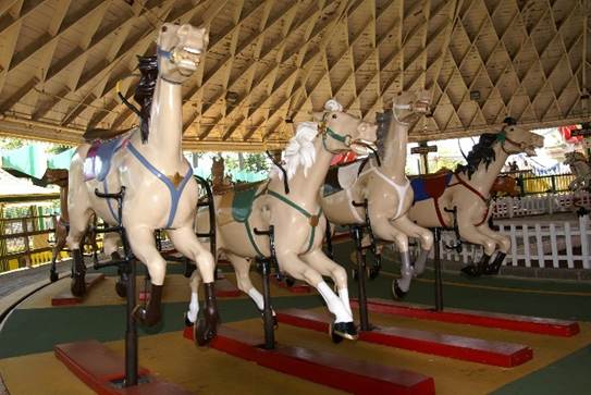 A group of horses in a merry go round
Description automatically generated