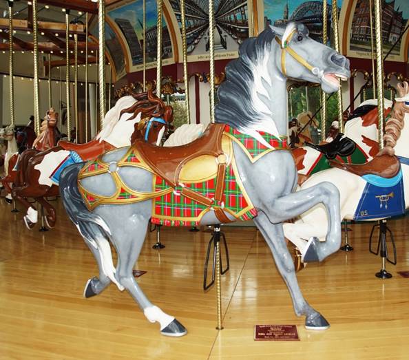 A carousel with horses on a wooden floor

Description automatically generated