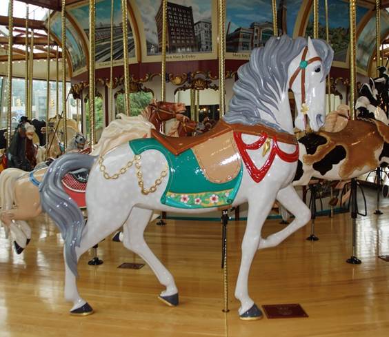 A carousel with horses on a wooden floor
Description automatically generated