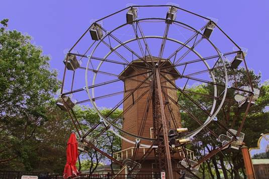 A ferris wheel in front of a building

Description automatically generated with medium confidence