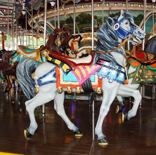 A carousel with horses on a wooden floor
Description automatically generated