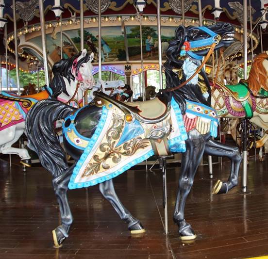 A carousel with horses on a wooden floor
Description automatically generated