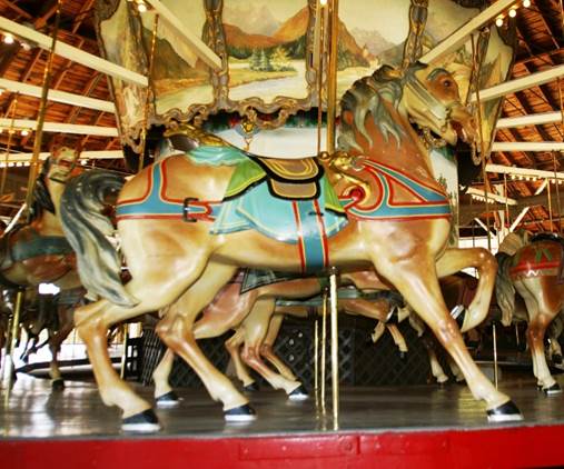 A carousel with horses on a red platform
Description automatically generated