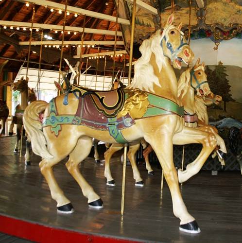 A carousel with horses on a wooden floor
Description automatically generated