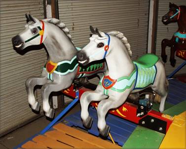 A pair of horses on a carousel

Description automatically generated