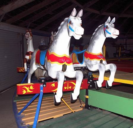 A group of horses on a merry go round
Description automatically generated
