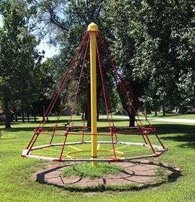 A playground swing in front of a tree

Description automatically generated