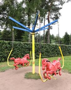 A playground swing in front of a tree
Description automatically generated